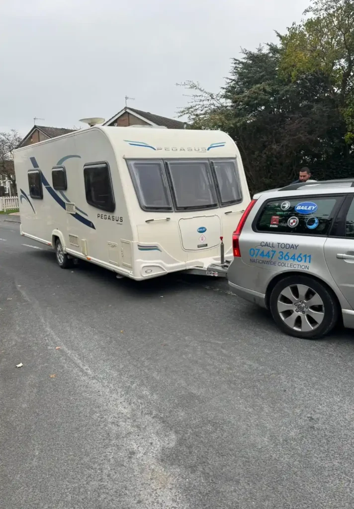 Touring caravan hitched to a liveried estate car for collection